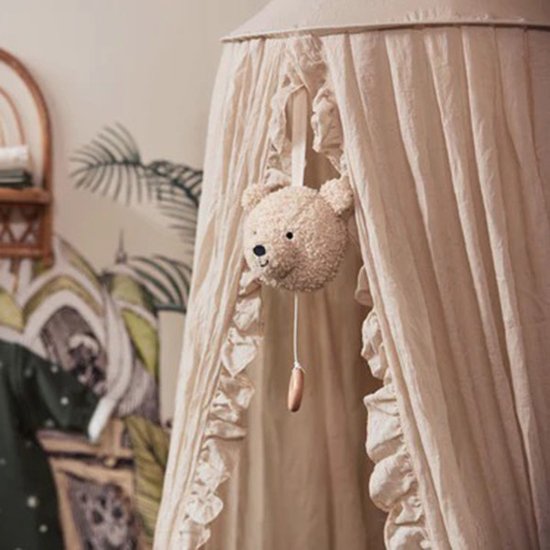 Muziekhanger teddybeer in naturelkleur hangt in een crèmekleurige hemel met ruches.