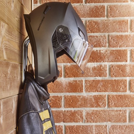 Grijze helm en zwarte leren jas hangend aan een zilverkleurige haak.