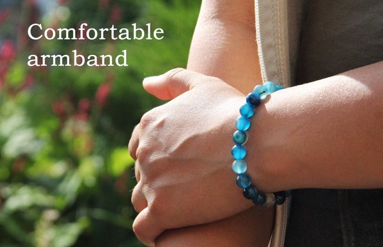 Een close-up van een pols met een blauwe en witte kralenarmband, tekst 'Comfortable armband'.