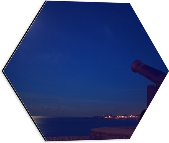 WallClassics - Dibond Hexagon - Kanon aan het Water bij de Rand van de Stad - 40x34.8 cm Foto op Hexagon (Met Ophangsysteem)