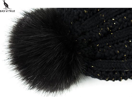 Close-up van een grote, donzige zwarte pompon op een gebreide muts met gouden glitters.
