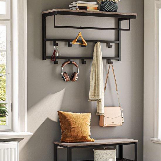 Kapstok met grijze houten plank en zwart metalen frame hangt boven een bankje. Kleding, hoofdtelefoon, sleutels en een tas hangen aan de kapstok. Boeken en vaas op de plank.