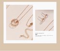 Close-up van een rosé-gouden ketting met cirkelvormige hanger bezet met strass steentjes en bijpassende oorbellen.