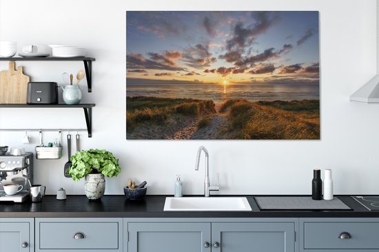 Cuisine avec des meubles de cuisine gris et sur le mur une toile d'un coucher de soleil sur les dunes.
