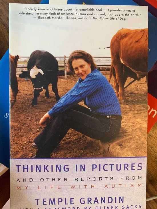 Boekomslag: Temple Grandin in blauwe blouse en spijkerbroek met koeien op de achtergrond. Titel: Thinking in Pictures.
