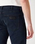 Close-up van de achterkant van een spijkerbroek met Wrangler-logo en stiksels op de achterzak.