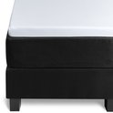 Een witte topper hoeslaken op een zwart matras, met zwarte pootjes.