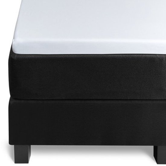 Een witte topper hoeslaken op een zwart matras, met zwarte pootjes.