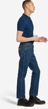Man in spijkerblauwe Wrangler spijkerbroek, recht model, gezien van de zijkant.