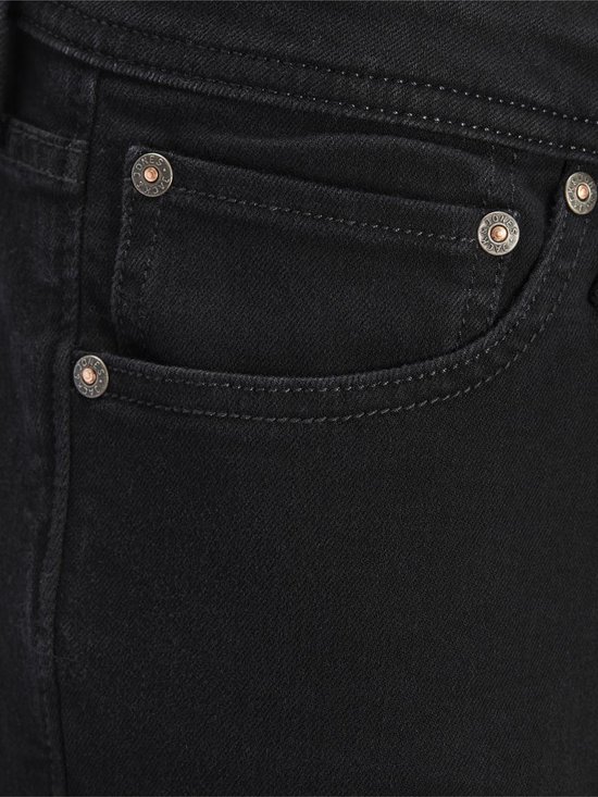 Close-up van de zakken van een zwarte skinny jeans voor heren met koperkleurige knopen.