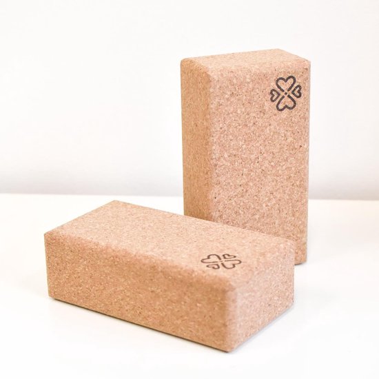 Twee kurken yogablokken op een witte ondergrond. Op de blokken staat een gestileerd hart-klaverblad logo.