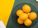 Zwarte metalen fruitschaal gevuld met sinaasappels, van bovenaf gezien.
