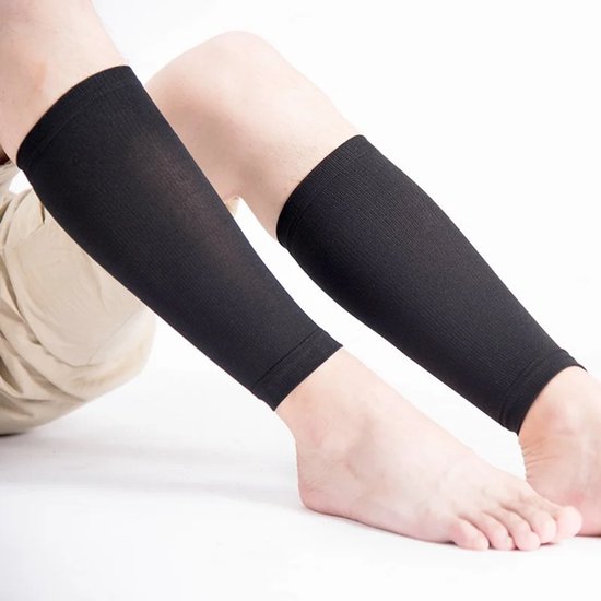 Zittende persoon met zwarte compressiekousen om de kuiten.