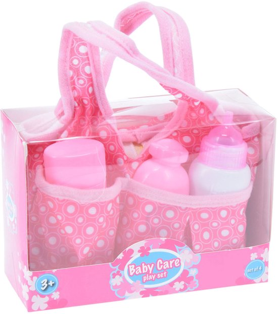 Roze draagtas met baby verzorgings set. Met flesjes en potjes in roze en wit, versierd met witte cirkels en bloemen.