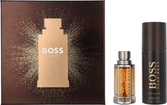 Geschenkdoos met "BOSS THE SCENT" erop, met een flesje amberkleurige eau de toilette en een zwarte deodorant spray ernaast.