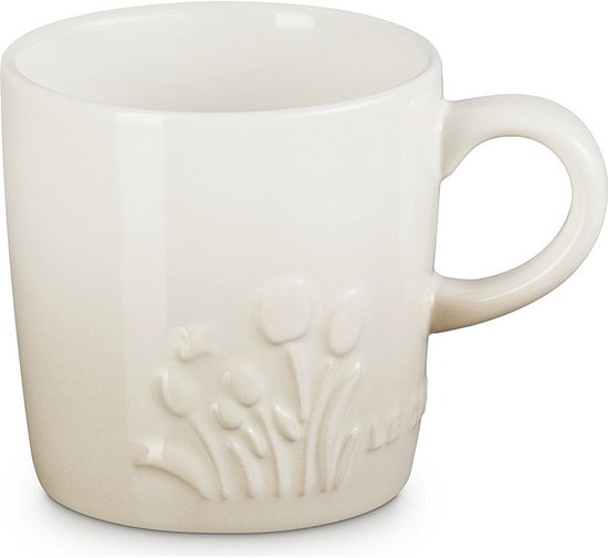 Mug Le Creuset blanc cassé avec tulipes en relief.