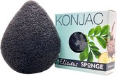 Een donkere, druppelvormige konjac spons naast een lichtgroene doos met de tekst KONJAC SPONGE.