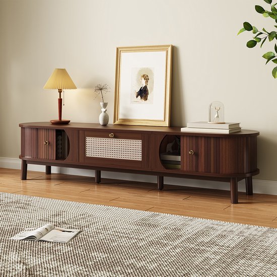 Donkerhouten tv-meubel met ronde vormen, rieten middenlade, messing knoppen en decoratie.