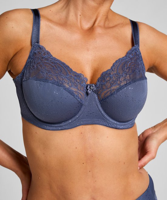 Blauwe beugel-bh met stippen, kanten bovenrand en strikje, gedragen door een model.