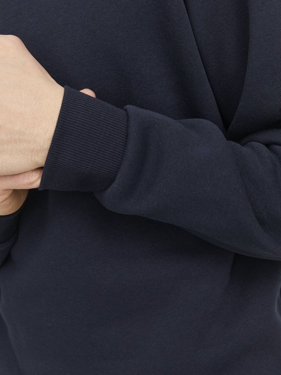 Detail van de geribbelde mouwboord van een donkerblauwe sweater.