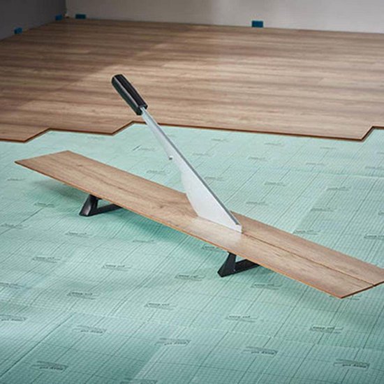 Laminaatsnijder LC 600 in gebruik op een groene ondergrond, met het mes op een houten plank.