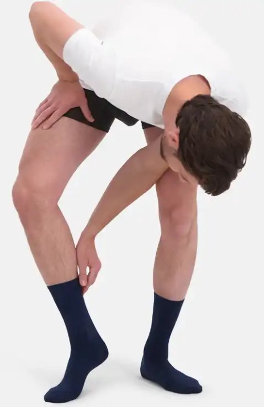 Man trekt een donkerblauwe sok aan. De sokken zijn tot halverwege de kuit.