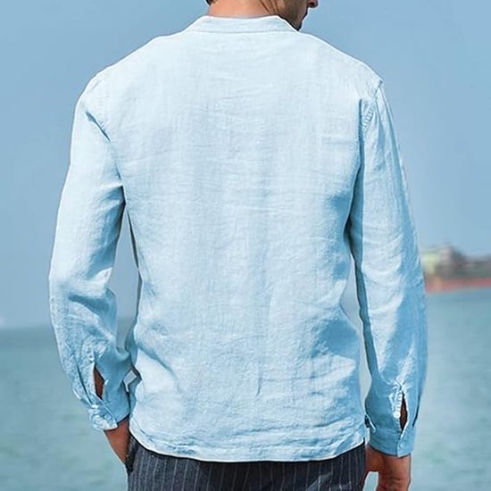 Achterkant van een man in een hemelsblauwe katoenen henley blouse met lange mouwen, staand aan de kust.