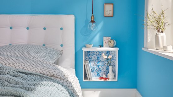 Chambre avec murs bleus, un lit et une table de chevet avec objets décoratifs.