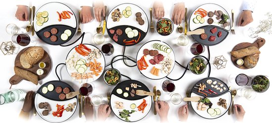 Twee gourmetstellen met eten erop, aan een tafel met mensen die eten.