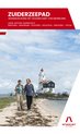 Twee wandelaars lopen op een pad langs het water met een vuurtoren op de achtergrond. De tekst luidt: ZUIDERZEEPAD, WANDELEN ROND HET GOUDEN HART VAN NEDERLAND.