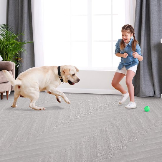 Lichtgrijze houtlook vloer in visgraatmotief in een lichte woonkamer waar een meisje met hond speelt.