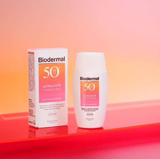 Biodermal Ultralichte Zonnefluide SPF 50+ verpakking en flesje op een rode en oranje ondergrond.