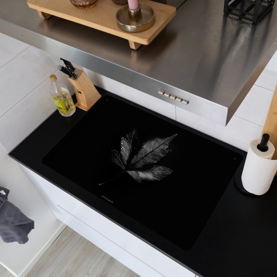 Protection d'induction noire avec imprimé feuille sur une plaque à induction dans une cuisine.