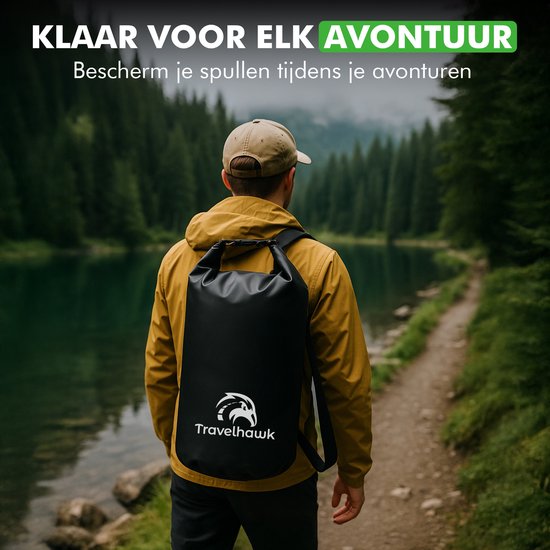 Zwarte Travelhawk drybag gedragen door een man in een gele jas, wandelend langs een meer in een bosrijk gebied.