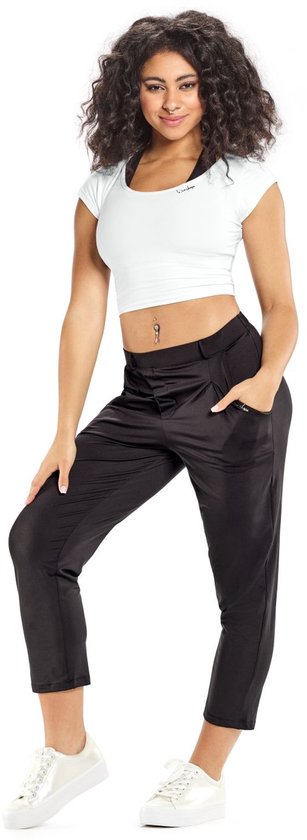 Model in strakke zwarte capribroek met wijde pijpen en witte crop top met korte mouwen.