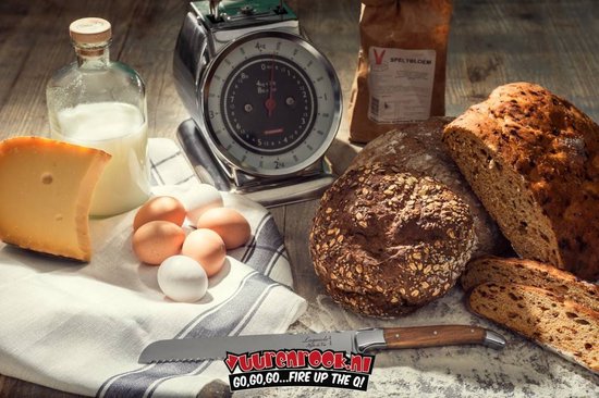 Brood, kaas, eieren, melk en een broodmes met olijfhouten handvat op een houten ondergrond.