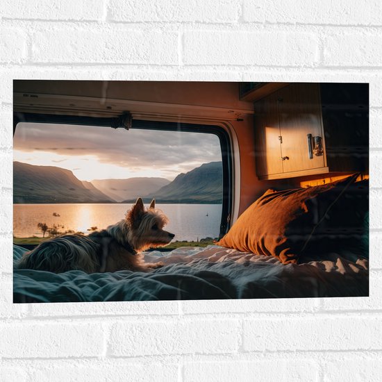 Muursticker - Puppy Liggend op Bed in Camper met Uitzicht op Meer - 60x40 cm Foto op Muursticker