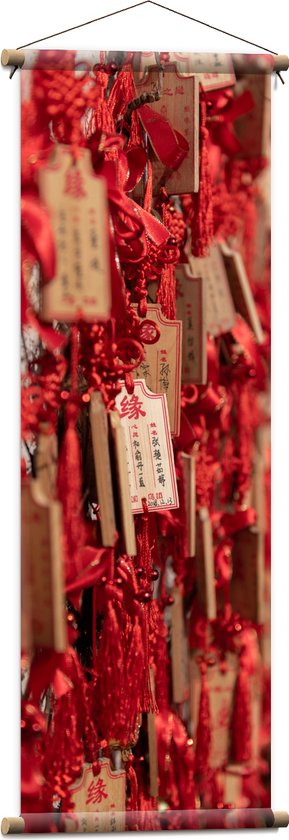 Textielposter - Rode Sleutelhangers met Chinese Tekens aan een Muur - 40x120 cm Foto op Textiel
