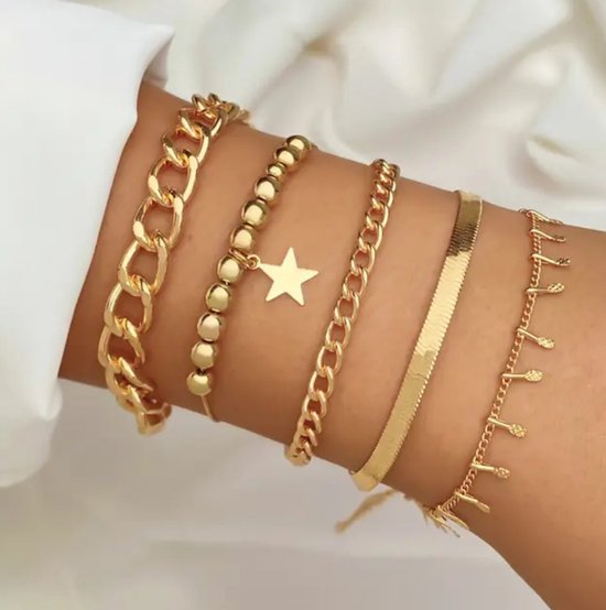 Gouden armbanden gedragen om een arm, met dikke schakels, kraaltjes, een ster en franjes.