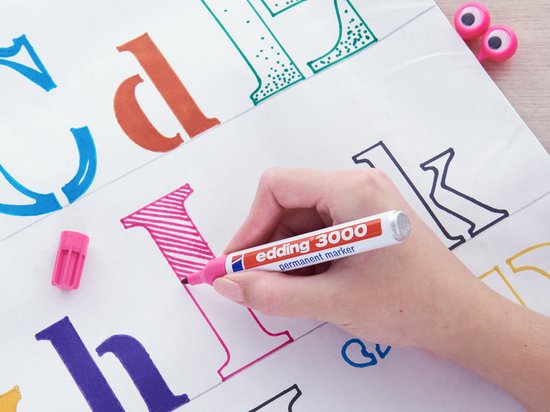 Hand met Edding 3000 marker kleurt de letter 'k' roze met strepen.