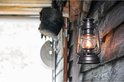 Zwarte Feuerhand lantaarn met vlam, hangend aan een houten muur.