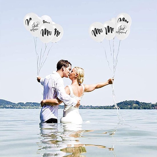 Bruidspaar kust in het water, elk een witte ballon met 'Mr', 'Mrs' of 'Just Married' vasthoudend.