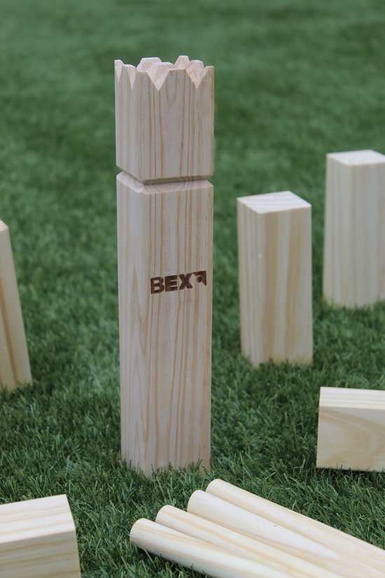 Een houten koningsstuk met de tekst BEX, staand op kunstgras met andere Kubb-blokken.