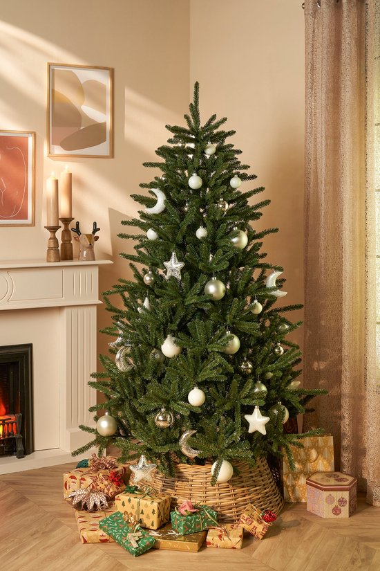 Gedecoreerde kunstkerstboom in een woonkamer, met witte en zilveren ballen, sterren en manen.