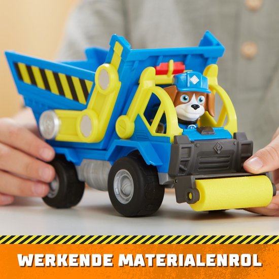 Kind handen bedienen een blauwe kiepwagen met gele onderdelen en een roller aan de voorkant. Tekst: WERKENDe MATERIALENROL.
