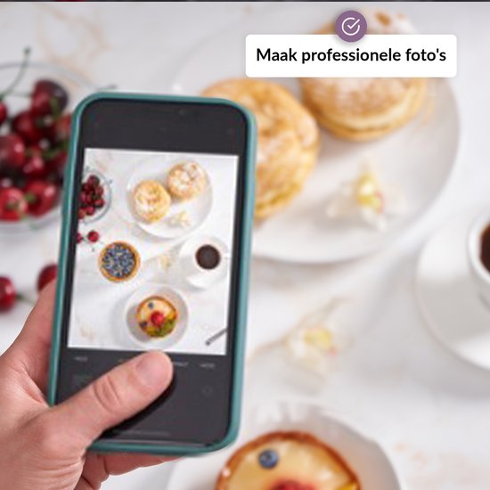 Een smartphone houdt een foto van gebakjes, een kopje koffie en kersen, met een marmeren achtergrond.