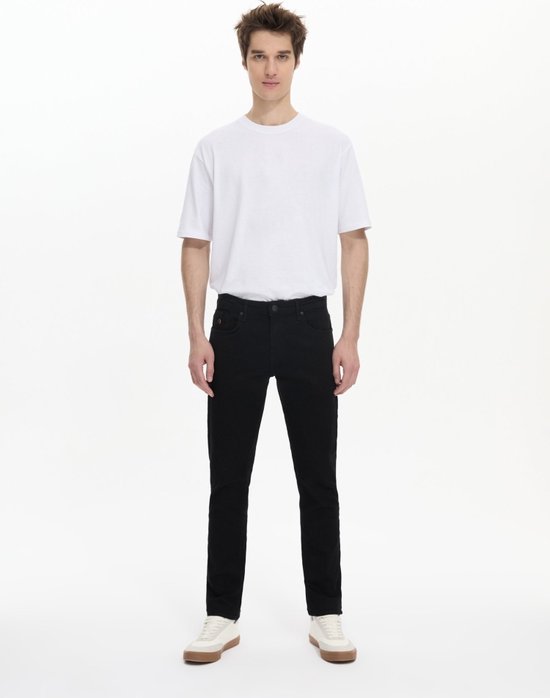 Man met witte t-shirt en zwarte LTB slim fit jeans, staand met witte sneakers.