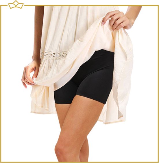 Onderkant van een beige jurk en de benen van een vrouw die een zwarte shapewear short draagt.