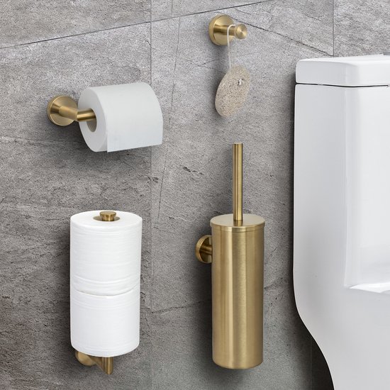 Gouden geborsteld RVS toiletaccessoireset aan een grijze tegelmuur: toiletrolhouder met twee rollen, toiletborstelhouder, handdoekhaakje en reserverolhouder naast een toilet.