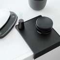 Een zwarte tampermat met daarop een doseerring, een tamper en een potje met 'BARISTA ESSENTIALS'.